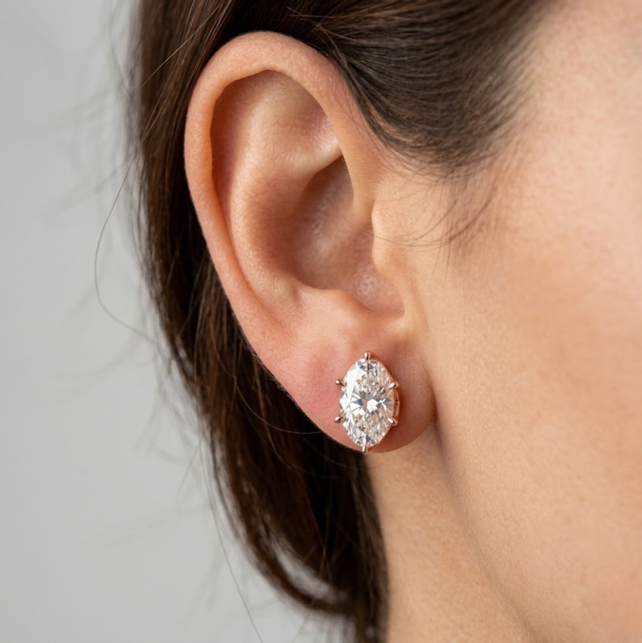 Close-up of an ear wearing a diamond earring with a neutral background, lab grown diamond in Hyderabad