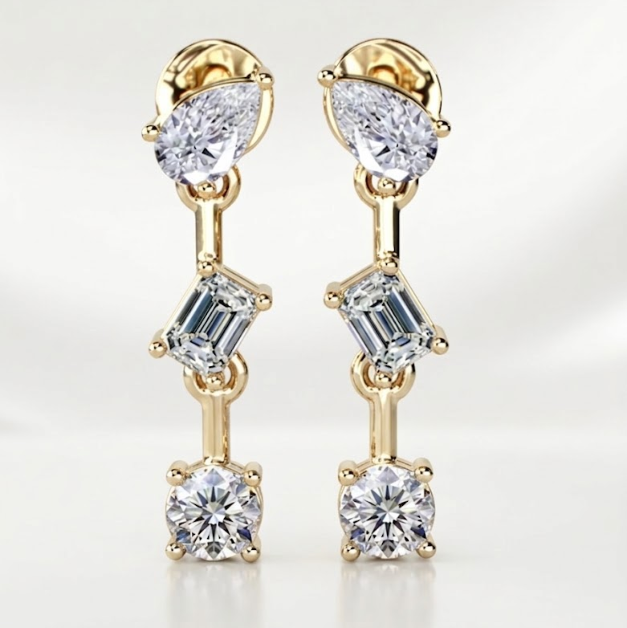Gold earrings with clear gemstones on a light gray background, lab grown diamond in Hyderabad