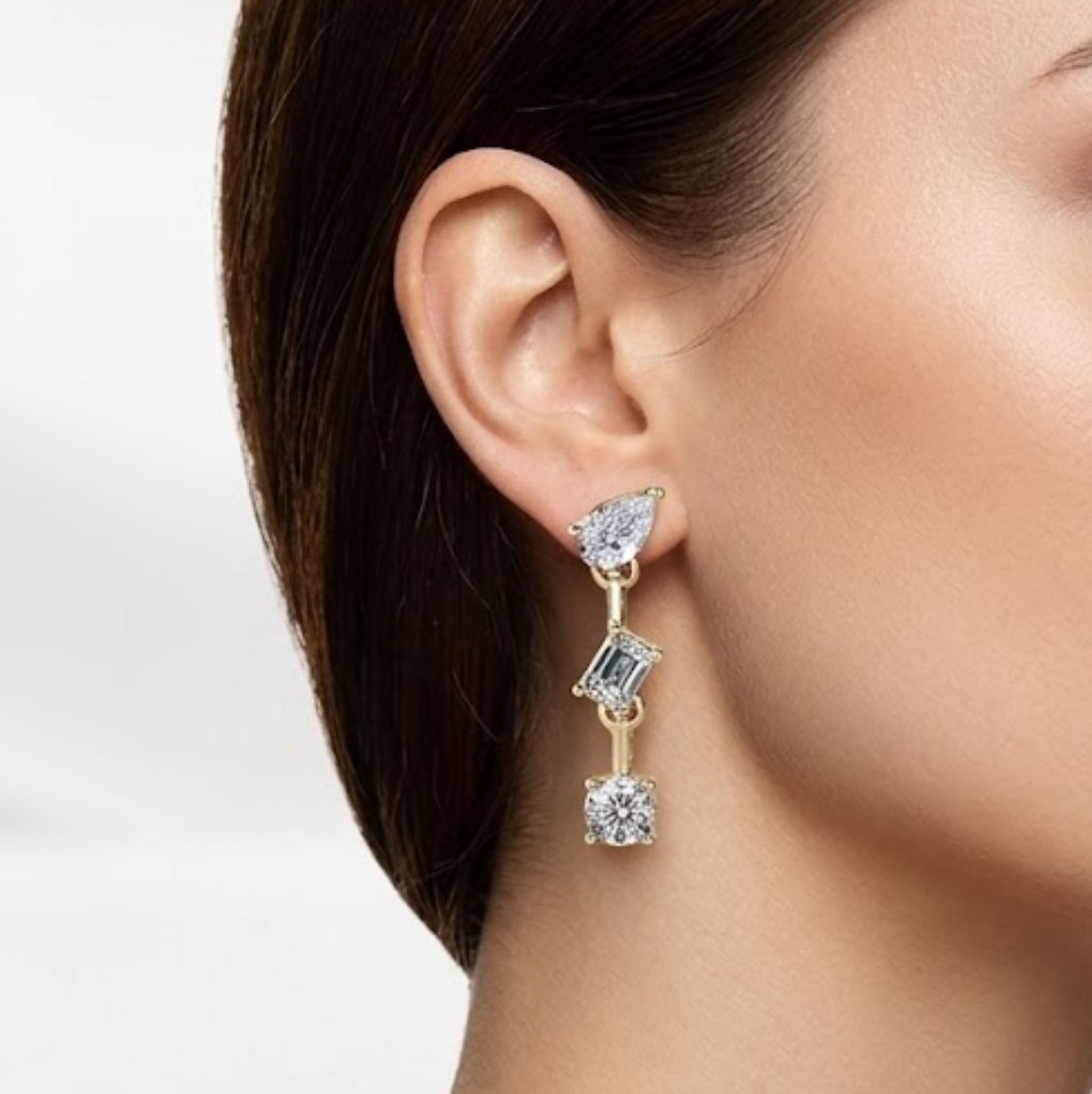Close-up of a woman wearing a gold earring with multiple gemstones on a white background, lab grown diamond in Hyderabad